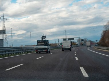 Venedik, İtalya 21 Kasım 2025 Otoyol A4 Serenissima otoyolunda altyapı ve ulaşımı gösteren bulutlu bir gökyüzüne karşı seyahat eden araçlar