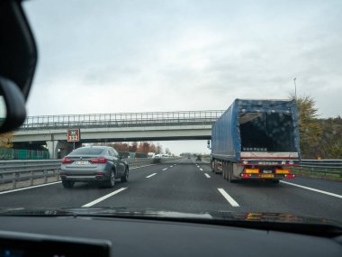 Venedik, İtalya 21 Kasım 2025 Otomobiller ve bir kamyon, bulutlu bir günde bir üst geçidin altında otoban hareketini ve ulaşım altyapısını gösteren A4 otoyolu boyunca seyahat ediyor.