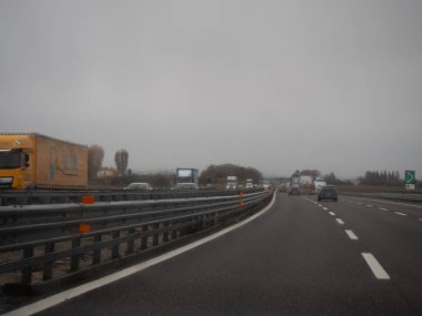 Venedik, İtalya 21 Kasım 2025 Otoyol trafiği İtalya 'da Autostrada A4' de. Kasvetli, sisli bir günde yoğun bir yolda giden araçlar, ulaşım teması