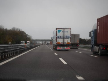 Venedik, İtalya 21 Kasım 2025 Italys Autostrada A4 boyunca hareket eden kamyon ve kamyonlar bulutlu bir gökyüzü altında, yoğun bir otoyol yolculuğunda yük ve yük taşırlar.