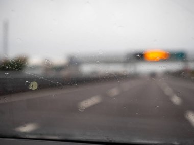 Venedik, İtalya 21 Kasım 2025 Yağmurlu bir günde yağmur damlalı araba ön camı, Bulanık İtalyan Autostrada A4 'ü gösteriyor.