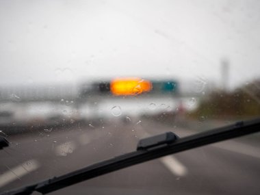 Venedik, İtalya 21 Kasım 2025 Yağmurlu bir günde bir otoyolda bir aracın içinde ıslak bir ön camda ilerleyen silecekler ve ilerideki bulanık trafik