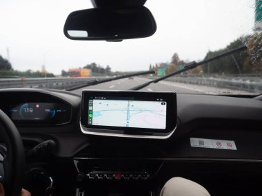 Venedik, İtalya 21 Kasım 2025 Sürücünün perspektifi bir otoyolda, gösterge paneli ve seyrüsefer sistemi ekranında yağmurlu bir günde yolculuğa rehberlik ediyor