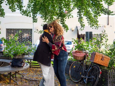 Kadın arkadaşlar parkta bisikletlerinin yanında kucaklaşıyorlar.