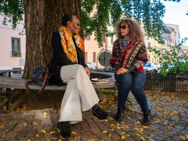 Sonbaharda arkadaşlar parktaki bankta konuşur ve dinlenir.