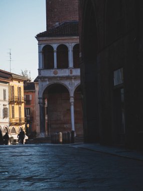 Cremona, İtalya 3 Ekim 2025 İtalyan tarihi caddesinde eski binalar, bir ortaçağ kulesi ve kaldırım taşları üzerinde yürüyen insanlar bir şehir manzarası yaratıyor.