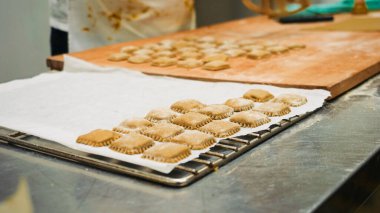 İşçi elleri, profesyonel bir mutfakta parşömen kaplamalı un tozlu ev yapımı ravioli hazırlıyor. Makarna hazırlıyor.