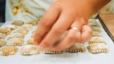 Şefin elleri geleneksel damgalı taze ravioli makarna eziyor, profesyonel bir mutfakta otantik İtalyan mutfağı hazırlıyor, mutfak geleneği ve becerilerini sergiliyor.