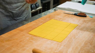 Taze makarna yapmak, ahşap bir yüzeye yayılmış küçük altın irmik hamur kareleri üzerine tuzlu dolgu yapmak, bölgesel spesiyalleri hazırlamak.