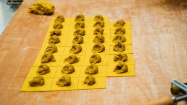 Taze makarna yapmak, ahşap bir yüzeye yayılmış küçük altın irmik hamur kareleri üzerine tuzlu dolgu yapmak, bölgesel spesiyalleri hazırlamak.