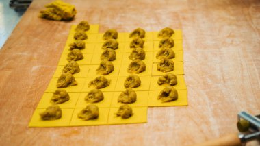 Taze makarna yapmak, ahşap bir yüzeye yayılmış küçük altın irmik hamur kareleri üzerine tuzlu dolgu yapmak, bölgesel spesiyalleri hazırlamak.