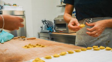Piacenza, İtalya - 5 Eylül 2025 Şef, profesyonelce doldurulmuş taze makarna hazırlıyor, profesyonel bir mutfakta tortellini yaratıyor, sanatsal süreci ve geleneksel İtalyan mutfağını gözler önüne seriyor