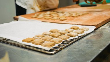 Soğutma sehpasında dinlenen taze mantı ve ahşap tahta ticari bir mutfak ortamında geleneksel İtalyan makarnası hazırlama sürecini gözler önüne seriyor.
