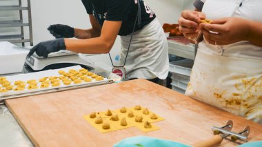 Piacenza, İtalya - 5 Eylül 2025 Taze, el yapımı tortellini ve ravioli hazırlamak için ellerini kullanan iki kadın hamurdan ve doyumdan kalite ve hassasiyeti güvence altına alıyor