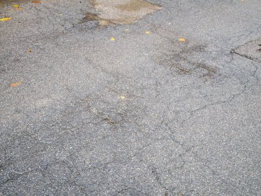 Koyu asfalt bir yüzeyi kaplayan sayısız küçük açık gri ve beyaz çakıl taşları kabataslak bir doku arkaplanı oluşturuyor