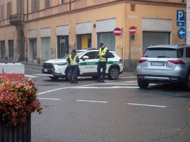 Cremona, İtalya - 9 Kasım 2025 İki İtalyan yerel polis memuru ve onların resmi devriye aracı Cremona İtalya 'da bir şehir caddesinde