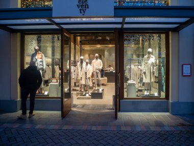 Fidenza, İtalya 5 Aralık 2025 Premium İtalyan günlük giysi ve aksesuar alışverişi. Perakende mankenlerinde kışlık paltolar, örgü giysiler ve pantolonlar sergileniyor.