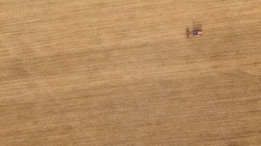 Uçsuz bucaksız kahverengi bir tarlada sürünen, düzleştirilmiş toprak tarlalarının, Tuscany kırsalında sürdürülebilir tarım ve tarım uygulamalarını gösteren havadan aşağıya doğru bakan eski traktör görüntüsü.