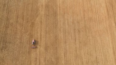 Traktör kuru bir alanda yeni sürülmüş toprağı düzleştiriyor, bahar tohumlama hazırlıkları sırasında toprağı işliyor, geleneksel tarım ve kırsal çalışmaları vurguluyor