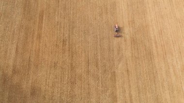 Traktör kuru bir alanda yeni sürülmüş toprağı düzleştiriyor, bahar tohumlama hazırlıkları sırasında toprağı işliyor, geleneksel tarım ve kırsal çalışmaları vurguluyor