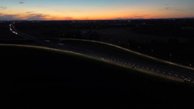 Piacenza Brescia karayolu kavşağında mavi saat boyunca akan A21 karayolu trafiği, araba ışık yolları ve şehir ışıkları akşam karanlığında hareket ve ulaşım kavramları yaratıyor.