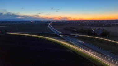 Gece Piacenza Brescia yakınlarındaki A21 otoyolu boyunca ilerleyen otoyol trafiği, alacakaranlık, ulaşım ve seyahat konsepti boyunca altyapı ve karayolu ağında ışık yolları oluşturan araçlar