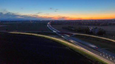 Gece Piacenza Brescia yakınlarındaki A21 otoyolu boyunca ilerleyen otoyol trafiği, alacakaranlık, ulaşım ve seyahat konsepti boyunca altyapı ve karayolu ağında ışık yolları oluşturan araçlar