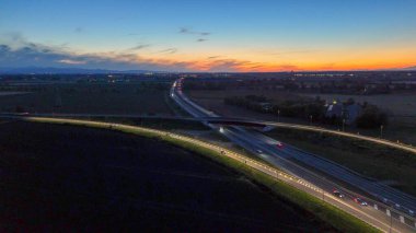 Gece Piacenza Brescia yakınlarındaki A21 otoyolu boyunca ilerleyen otoyol trafiği, alacakaranlık, ulaşım ve seyahat konsepti boyunca altyapı ve karayolu ağında ışık yolları oluşturan araçlar