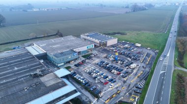 Vescovato, İtalya 7 Aralık 2025. Hava manzarası Pepco ve Tigota gibi perakende mağazaları, büyük bir park yeri ve sisli bir gündoğumu sırasında birbirine bağlı bir yol gösteriyor.