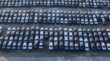Otomotiv endüstrisi üretimi, ihracat lojistiği ve pazarlara dağıtımdan önce depolama kavramlarını sembolize eden geniş bir park alanını dolduran yeni araba sıraları