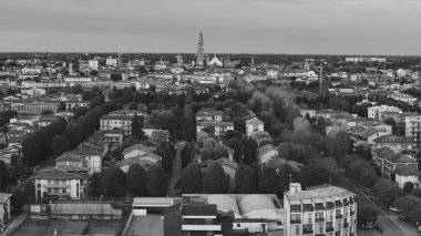 Kremona Katedrali 'nin Torrazzo' suyla gün batımında İtalya 'nın Lombardy şehrinde gökyüzü renklerle kaplanırken, konut binaları, ağaçlar ve uzun düz bir yol görülebiliyor.