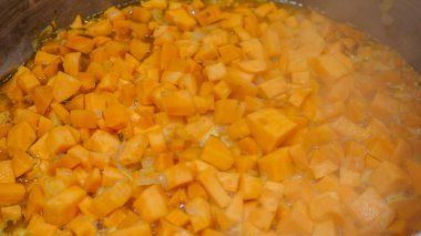Lezzetli patates çorbası ve geleneksel Afrika güveci hazırlıyorum. Profesyonel bir mutfakta sıcak bir tencerede doğranmış portakal sebzesi pişiriyorum. Sağlıklı malzemelere ve canlı renklere odaklanmak