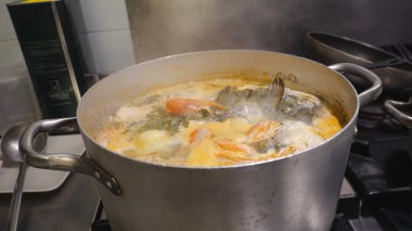 Professional kitchen preparing traditional African sweet potato broth, shrimp, and fish soup boiling in a pot on the stove, creating an authentic and warm culinary experience