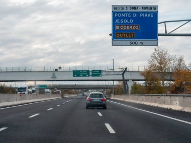 Bir otoyolda, Jesolo ve Oderzo 'yu gösteren bir çıkış işareti olan bir araba sürüyor. Bir seyahat ve yolculuk anını yakalıyor. Vicenza, İtalya - 21 Kasım 2025