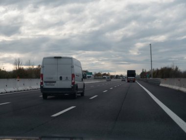 Kasvetli bir günde bulutlu bir gökyüzü olan araçlarla dolu otoyol sahnesi Vicenza, İtalya - 21 Kasım 2025