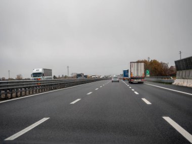 Araçlar yoğun bir otoyolda bulutlu bir gökyüzünün altında, günlük gidiş-dönüş ve ulaşım aktivitelerini yakalıyorlar. Vicenza, İtalya - 21 Kasım 2025