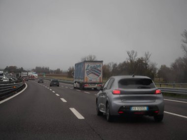 Tramvaylar kasvetli bir günde yoğun bir otoyolda ilerlerken, kamyonlar ve araçlar İtalya 'nın Vicenza kentindeki yolu paylaşıyor. 21 Kasım 2025