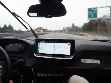 Otobanda sürerken ekranda GPS navigasyonu olan modern araba iç mekanı, yolda teknoloji ve konfor sergiliyor. Vicenza, İtalya - 21 Kasım 2025