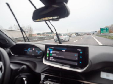 Modern bir araba iç mekanıyla otoyolda sürerken çekilmiş bir görüntü, gösterge paneli ve navigasyon ekranını gösteriyor. Vicenza, İtalya - 21 Kasım 2025