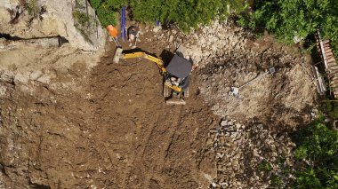 İnşaat işçileri, şehir merkezindeki yıkım çalışmaları sırasında bir kazıcı işletiyorlar, enkazı temizliyorlar ve yeni inşaat sahasına hazırlanıyorlar.