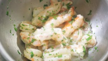 Bir şef, pişirilmiş karidesi ince doğranmış maydanozla karıştırarak deniz ürünleri yemeği hazırlıyor.