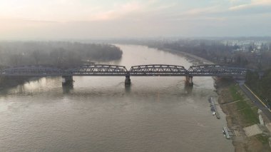 İtalya 'nın Cremona kentindeki Po Nehri' nin geniş bir manzarası. Suyu sisli bir gökyüzünün altında uzanan tarihi çelik kiriş köprüsü.