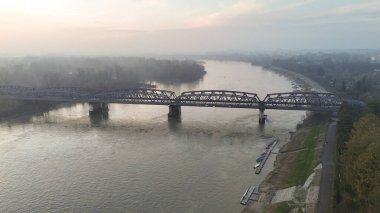 Geniş bir insansız hava aracı atışı, İtalya 'nın Cremona kentinden geçen Po Nehri' ni, yumuşak ve sisli bir gökyüzünün altından geçen seçkin çelik bir köprüyle yakalıyor.