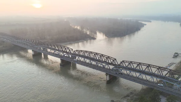 İtalya 'nın Cremona kenti yakınlarındaki Po Nehri üzerindeki çelik demiryolu köprüsünün geniş bir manzarası şafağın yumuşak ışığında yıkandı.
