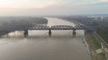 Geniş bir hava perspektifi, Po Nehri 'nin sisli bir gökyüzü altında uzanan tarihi bir kiriş köprüsü ile İtalya' nın Cremona kentinden akışını yakalar.
