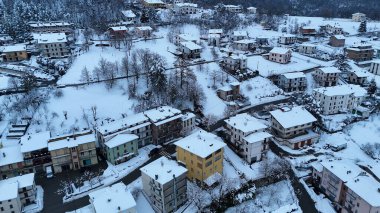 Zarif bir kış sahnesi sergilenirken kar, büyüleyici bir İtalyan dağ köyünün çatı ve sokaklarını örtüyor. Huzurlu güzelliğini sergiliyor Le Bore, PR, İtalya