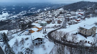 Kışın el değmemiş beyaz karla kaplanmış büyüleyici bir İtalyan dağ köyünü, Le Bore, PR, İtalya manzarasını süsleyen evlerle bir hava manzarası yakalıyor.