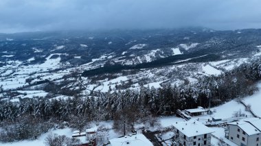 İtalya 'nın Apennine dağlarındaki sakin kış manzarasının havadan görünüşü dağınık evler ve yoğun ormanlarla kaplı taze karla kaplı Le Bore, Halkla İlişkiler, İtalya