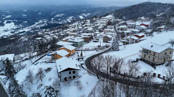 Kışın el değmemiş beyaz karla kaplanmış büyüleyici bir İtalyan dağ köyünü, Le Bore, PR, İtalya manzarasını süsleyen evlerle bir hava manzarası yakalıyor.