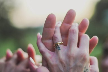 Dövmeli eller, sakin bir açık havada bir araya getirilmiş evlilik yüzüğüyle sevgi ve bağlantı taşırlar.